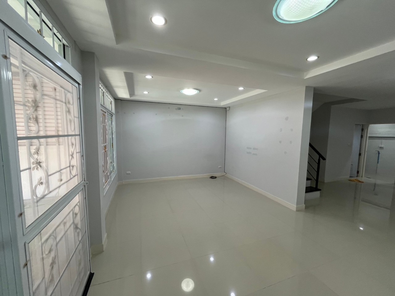 ห้องนั่งเล่นชั้นล่างสีสว่างพร้อมหน้าต่างบานใหญ่